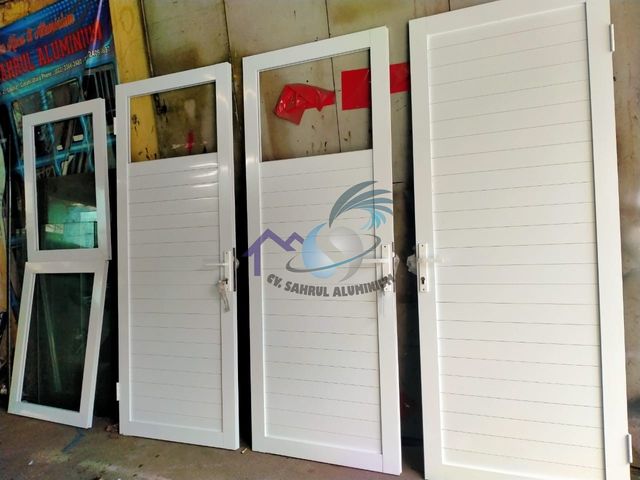 Proses produksi dan perakitan pintu panel aluminium putih di workshop CV. Sahrul Aluminium